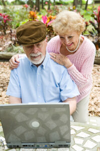 Happy senior couple using their laptop computer outdoors.